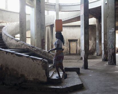 Una mujer acarrea agua por una de las dos escaleras de la entrada principal. En este vestíbulo en otros tiempos lujoso, todo estaba listo para dar la bienvenida a inversores internacionales y ricos turistas blancos de los países vecinos, Rhodesia (ahora Zimbabue) y Sudáfrica.