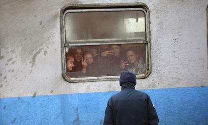 Un polic&iacute;a croata frente a un grupo de inmigrantes en un tren, este viernes cerca de la frontera con Serbia.