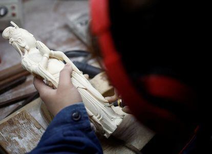 Una mujer trabaja sobre una pieza de marfil en un taller de Pekín (China).