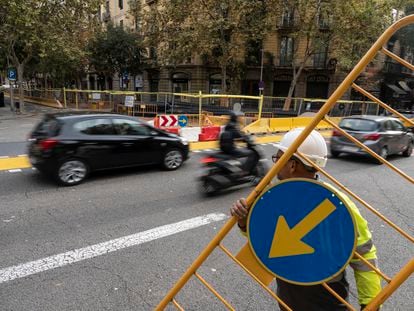 Momento en el que varios operarios ponen vallas para indicar que la calle de Consell de Cent, a la altura de Pau Claris, en Barcelona, ya no se puede cruzar en línea recta y es obligatorio girar en cada esquina.