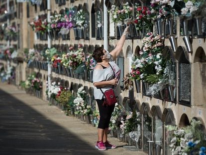 Una mujer deposita flores, en un cementerio de Barcelona, este lunes.