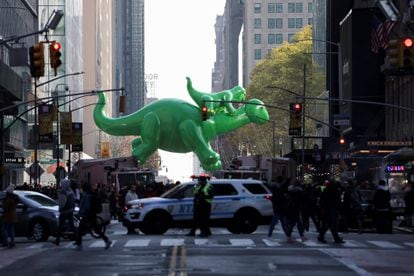 Desde la primera edición, celebrada en 1927, algunos de los personajes más populares del mundo son convertidos en globos gigantes que sobrevuelan la ciudad. En la imagen, un globo del dinosaurio Dino con un bebé en hombros, durante el desfile de este jueves. 