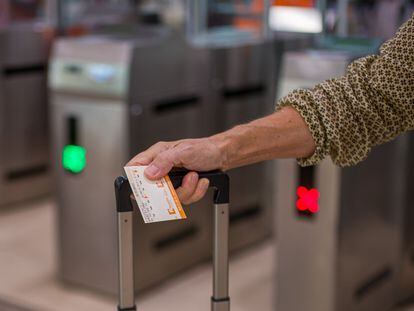 Una viajera sostiene un billete tras cruzar los tornos de una estación.