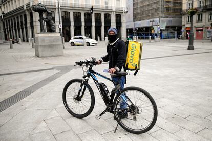 El repartidor de Glovo José, de Venezuela, posa junto a su bici en la Puerta del Sol en Madrid.