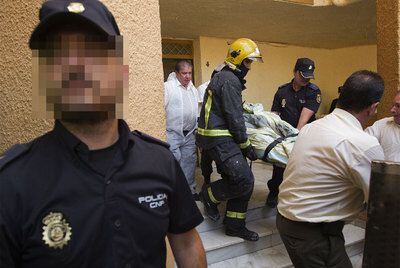 Bomberos y policías retiran el cuerpo de uno de los fallecidos de la vivienda incendiada.