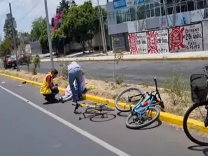 Dos hombres auxilian a uno de los ciclistas que fueron arrollados este domingo en Puebla.