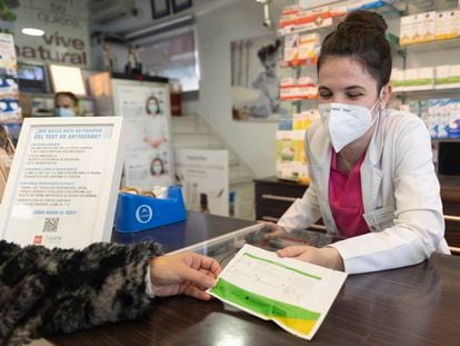 Una farmacéutica muestra un test de antígenos a una persona en la farmacia ‘Las Gemelas’, a 10 de enero de 2022, en Madrid.