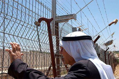 Un palestino mira a través de la verja fronteriza el asentamiento israelí de Metulla.