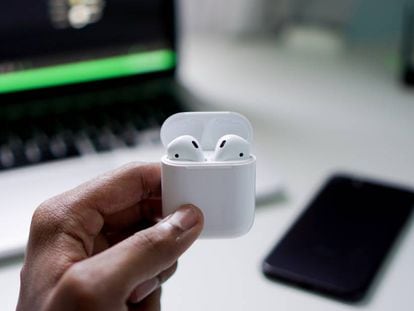 Un hombre sujeta los auriculares 'true wireless' AirPods V2, de la marca Apple.