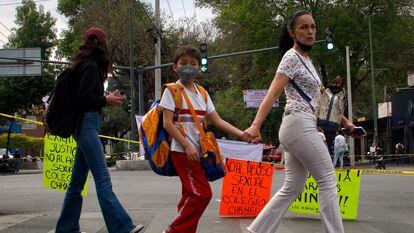 Una mujer y un menor, en uniforme escolar, caminan frente al bloqueo que realizaron los padres del Colegio Carmel en la colonia Granjas Coapa (Ciudad de México) el 1 de marzo.