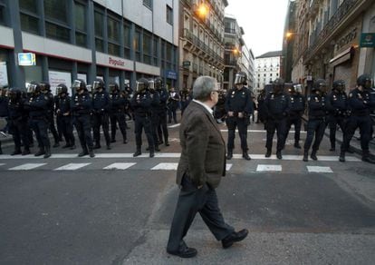 Un hombre cruza frente al dispositivo policial que vigila la marcha &#039;Rodea el Congreso&#039; convocada por la Coordinadora 25-S, para protestar por la investidura de Mariano Rajoy como presidente del Gobierno.