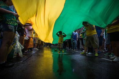 Un niño camina bajo una bandera en la manifestación de Sao Paulo, Brasil.