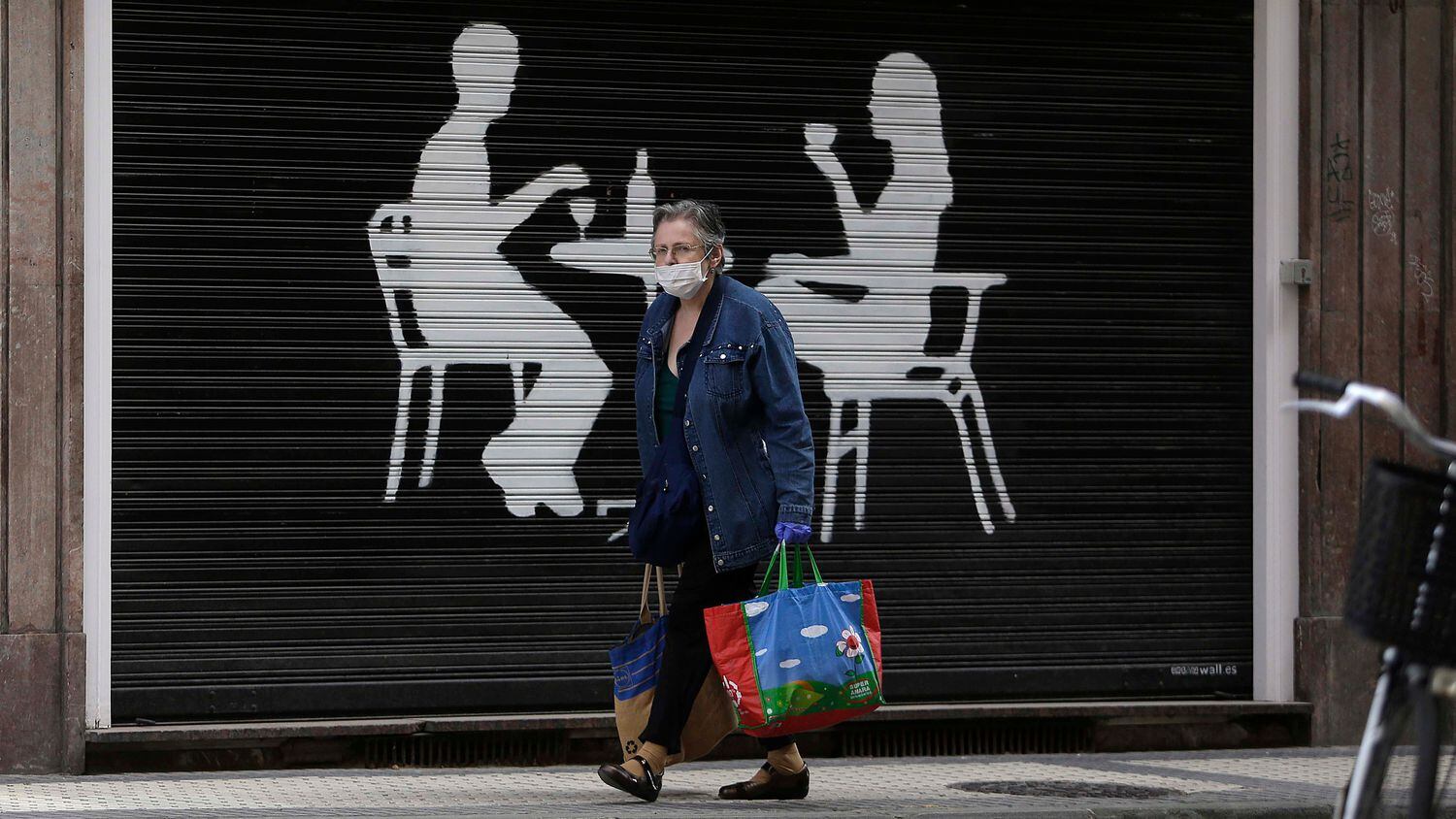 Una mujer pasa con la compra frente a un bar cerrado en San Sebastián.