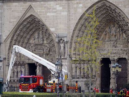 Grupos de bomberos trabajan ante la fachada de la catedral de Notre Dame, esta mañana.