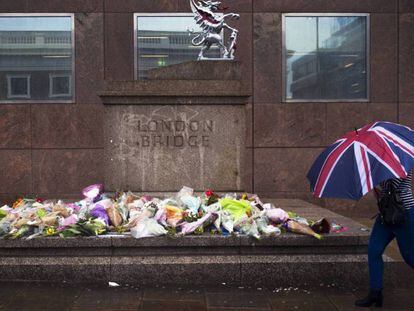Una mujer pasa delante de varios ramos de flores dejados en memoria de las víctimas del atentado del sábado en el Puente de Londres.