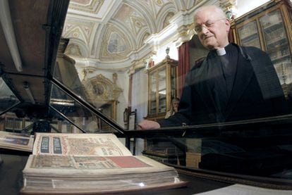 El deán José María Díaz observa una edición facsímil del <i>Códice Calixtino,</i> expuesta en la catedral en sustitución de la obra robada.
