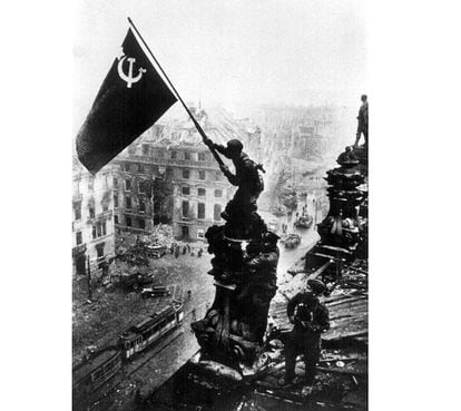 Otra de las fotos más reproducidas de la II Guerra Mundial tomada por Yevgueni Jaldéi, que muestra a soldados del Ejército Rojo alzando la bandera soviética sobre las ruinas del Reichstag durante la caída de Berlín, el 2 de mayo de 1945.