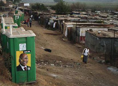 Una mujer observa unos baños públicos donde hay publicidad electoral de Jacob Zuma en Johanesburgo.