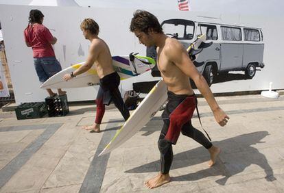 Dos surfistas pasan junto un mural que pinta un joven, ayer en la salida de la playa de Zarautz.