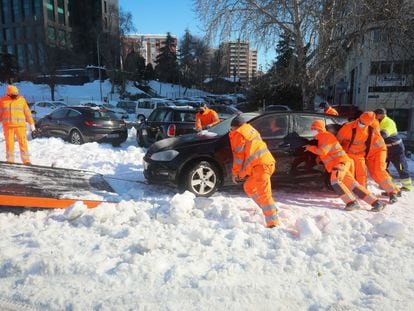 Los servicios de emergencia retiran un vehículo atrapado en la nieve, en Madrid. 