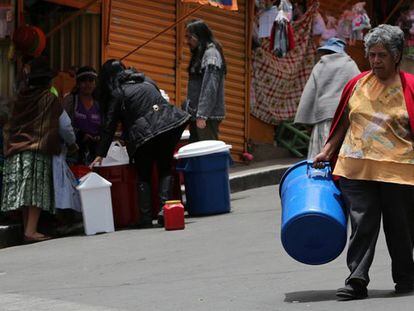 Una ciudadana de La Paz camina con un recipiente para recibir agua.