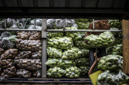 Trabajadores transportan vegetales a un mercado de Manila, Filipinas.