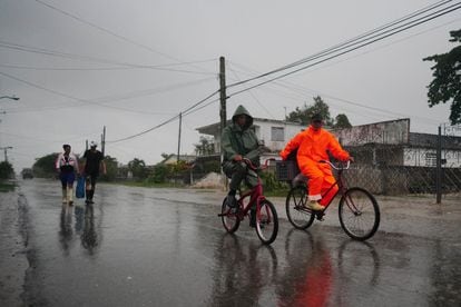 Un grupo gente caminaba bajo la lluvia antes de la llegada del huracán 'Ian' en Coloma, el lunes.