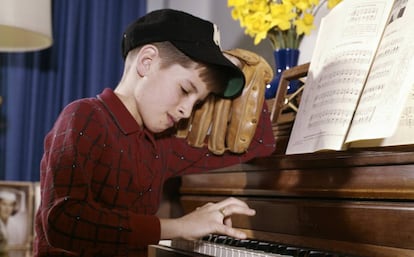 Ni&ntilde;o en clase de piano, pero deseando jugar al b&eacute;isbol 