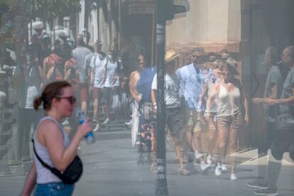 Un grupo de turistas se refleja en un escaparate del casco histórico de Sevilla, este martes.