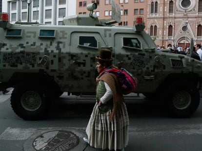 Una mujer camina frente a una tanqueta en el centro de La Paz.