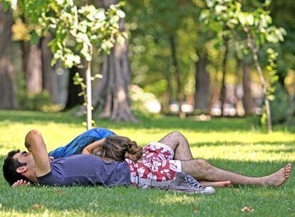 Una pareja duerme la siesta a la sombra de un árbol en el parque del Retiro en Madrid.
