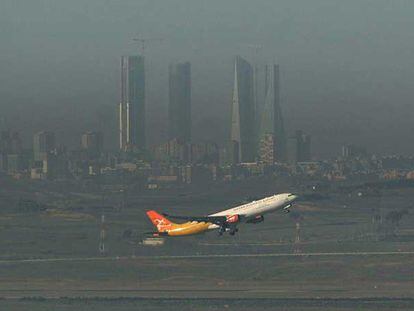 Un avión despega entre la nube de polución, que desdibuja las torres del Real Madrid.