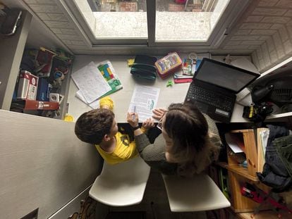 Un niño estudia y hace los deberes en casa con la ayuda de su madre. 