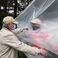 Un hombre abraza a su padre a través de un plástico en la celebración del día de los caídos en Wantagh, Nueva York, este domingo.