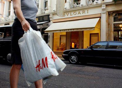 Una mujer carga con dos bolsas de la tienda H&amp;M en Londres