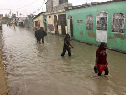 Un grupo de personas caminan por las calles inundadas de Puerto Príncipe.
