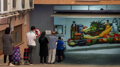 Varias personas, a la espera de recoger alimentos en el almacen de la Cruz Roja en Mataró (Barcelona).