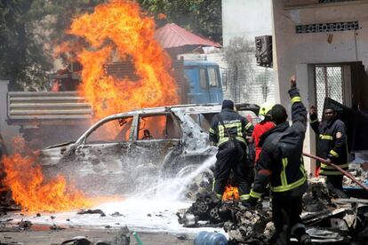 Bomberos somalíes intentan apagar el fuego ocasionado por la explosión de un coche bomba cerca de un restaurante, en Mogadiscio.