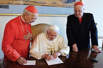 El Papa firma un documento en presencia de los cardenales Angelo Sodano (derecha) y Eduardo Martínez Somalo.