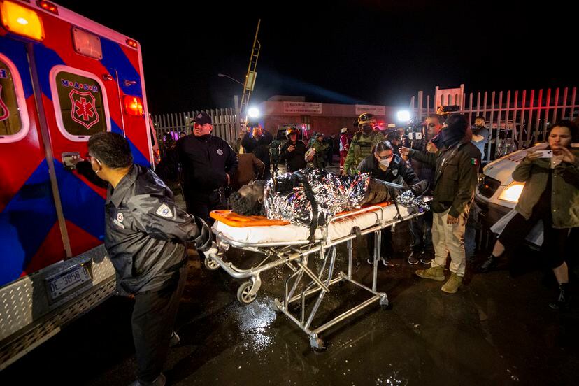 Un migrante es trasportado por paramédicos a una ambulancia, luego del incendio en el centro del INM.