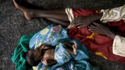 Un niño malnutrido en el suelo junto a su madre en el campo de desplazados de Abu Shouk en Sudán.
