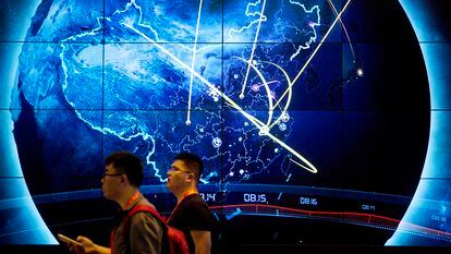 Attendees walk past an electronic display showing recent cyberattacks in China at the China Internet Security Conference in Beijing