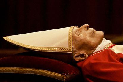 Benedicto XVI ha sido ataviado de rojo papal, pero sin el palio: el ornamento que se coloca al cuello y que indica el poder ejercido en el momento de su muerte. La ausencia de dicha pieza señala que el alemán, justamente, estaba retirado.