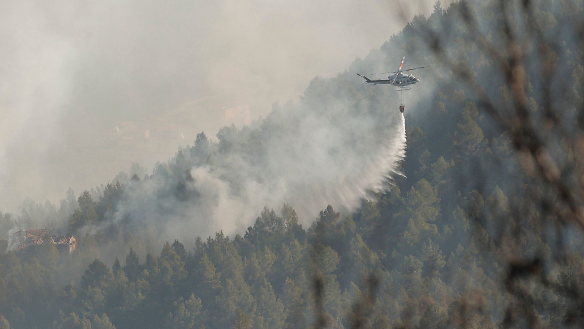 Un helicóptero trabaja en la extinción del incendio en la zona de los Peiros, en la provincia de Teruel, este sábado.