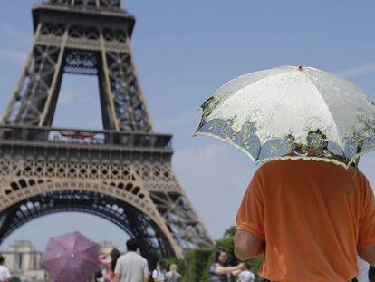 Varios turistas se protegen con sombrillas del calor, frente a la Torre Eiffel de Par&iacute;s, Francia. 