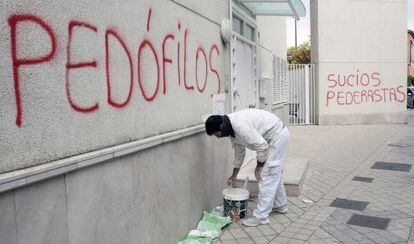 Un pintor tapa una pintada a la parròquia on exercia el pare Román el novembre del 2014.