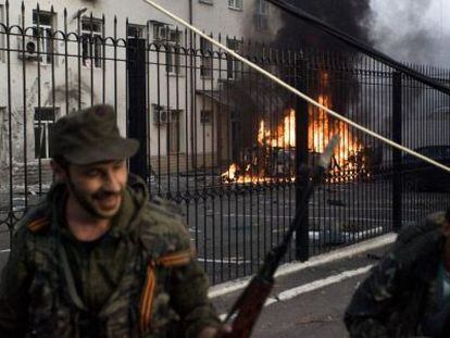 Separatistas prorrusos se alejan de un carro ardiendo en Donestk.