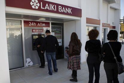 Clientes del Laiki Bank de Larnaca (Chipre) hacen cola en el cajero automático, ayer sábado por la mañana