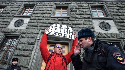 Un hombre sostiene un cartel con el lema "Putin, dimisión", frente a la sede el FSB en Moscú, este sábado, poco antes de ser detenido.