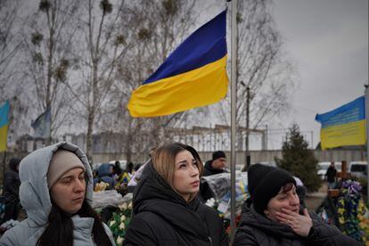 Anastasiya (centro), de 27 años, ante la tumba de su marido en el cementerio de Bucha, Yuri, que perdió la vida en el frente del este de Ucrania en agosto pasado. 